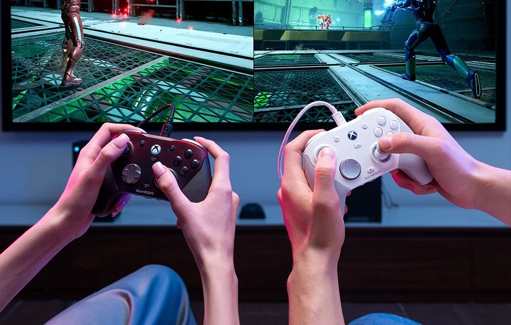Lähikuva kahden ihmisen käsistä, joissa on GameSir-ohjaimet television ääressä pelatessa.