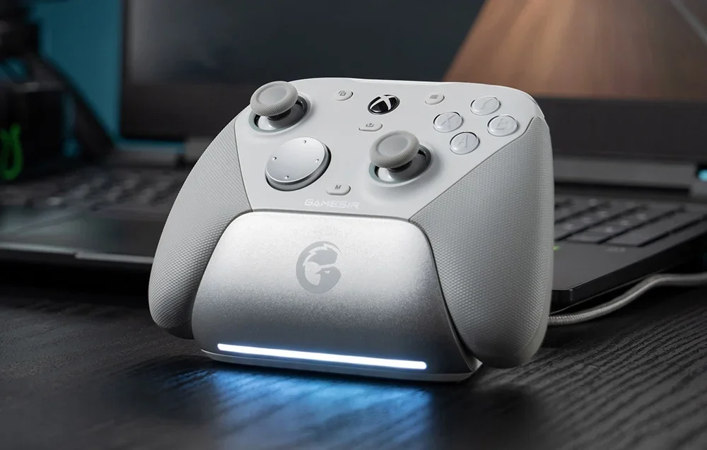 Valkoinen GameSir-ohjain latausasemassa kannettavan tietokoneen edessä.