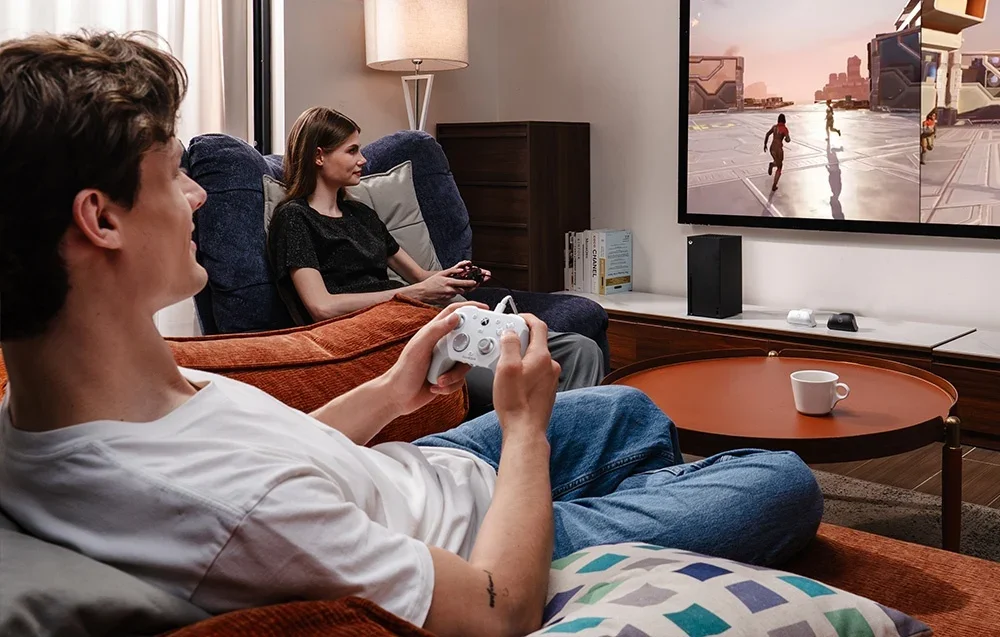 Kaksi ihmistä pelaa televisiolla GameSir-ohjaimilla, toinen valkoisella ja toinen mustalla.