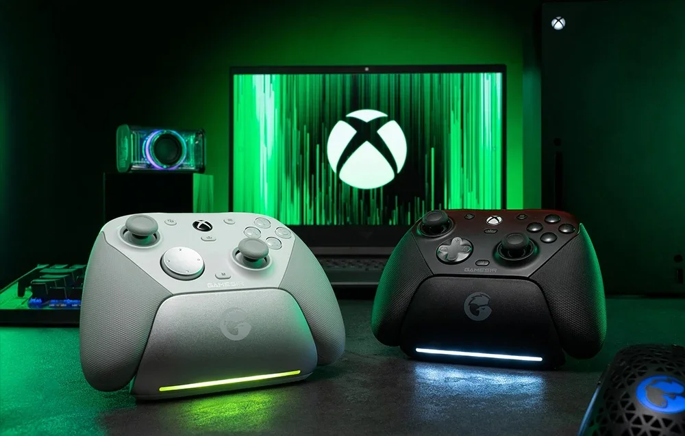 Kaksi GameSir-ohjainta telakassa Xbox-logolla varustetun näytön edessä, yksi valkoinen ja toinen musta.