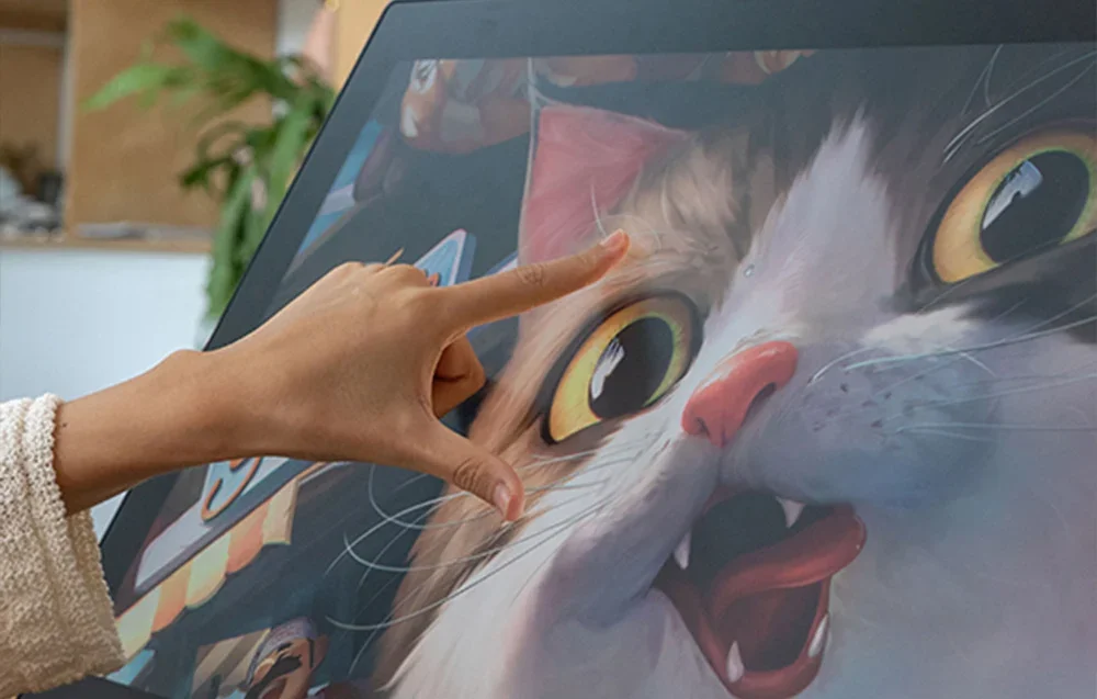 Lähikuva Huion-grafiikkatabletista, jonka kissakuvitusta suurennetaan sormilla.