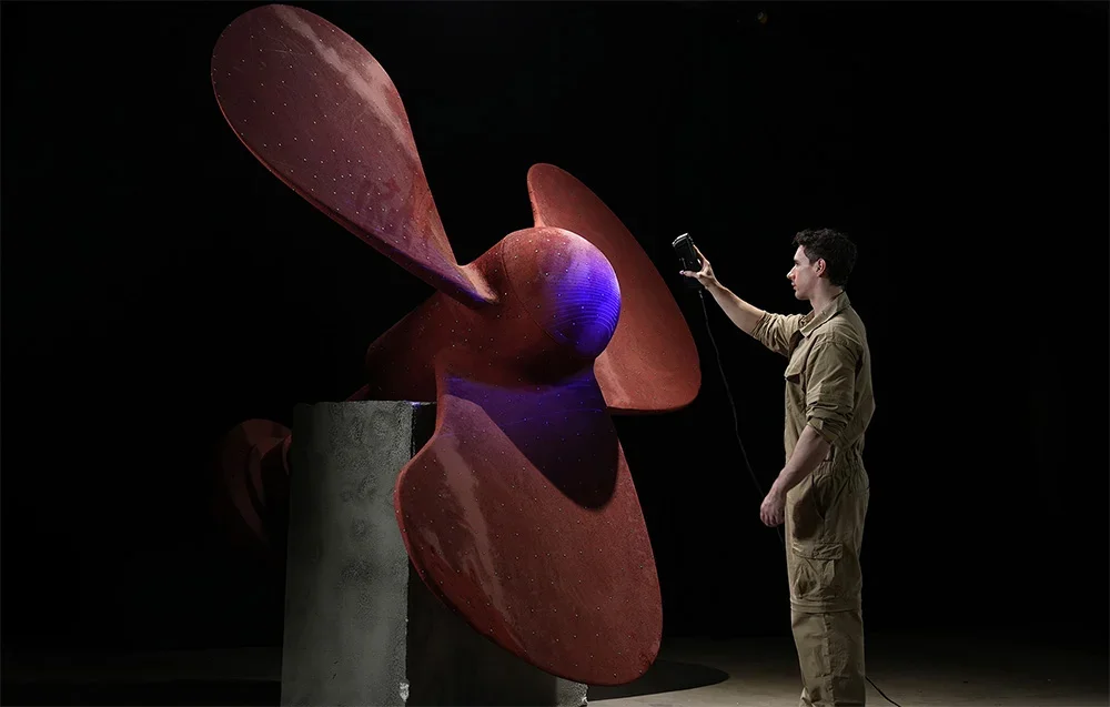 Teknikko skannaa suurta punaista laivan potkuria 3D scanner -laitteella